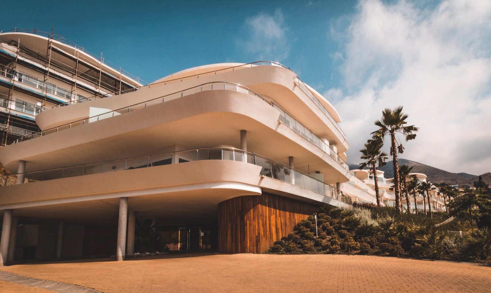 Curved white terraces of a Benalmádena residence against a blue sky with palms